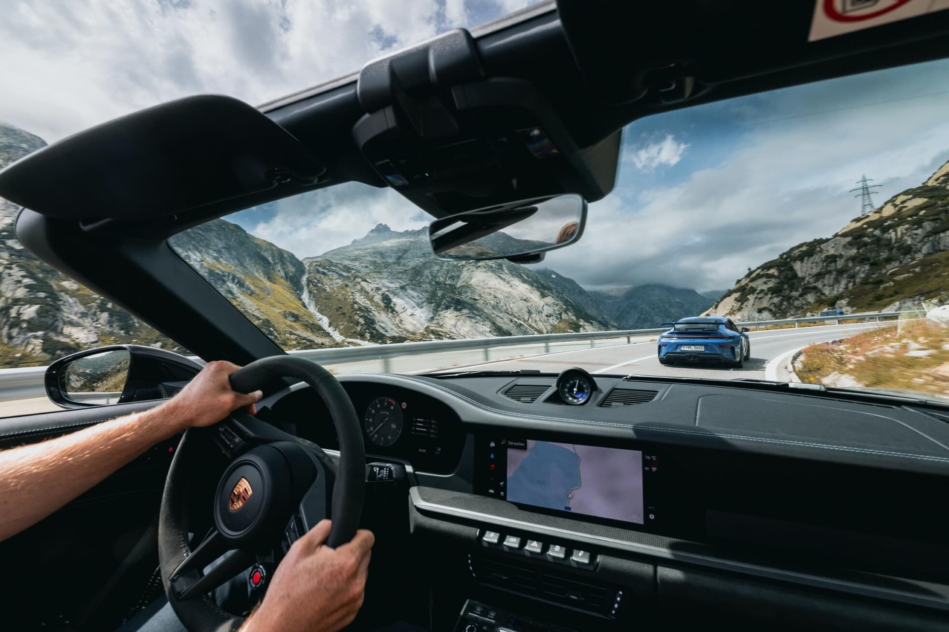 Driver's hands on the steering wheel of a Porsche 911